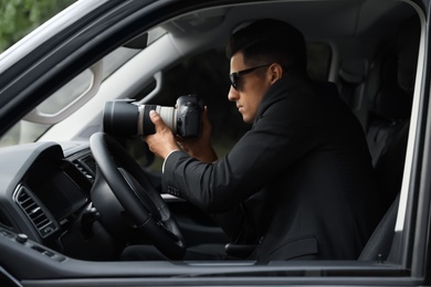 Photo of Private detective with camera spying from car