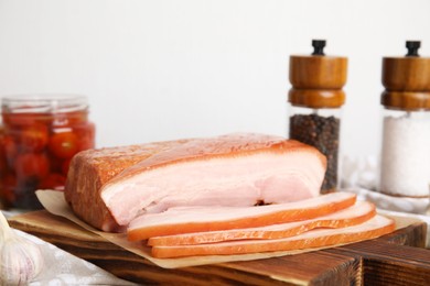 Photo of Delicious smoked bacon on wooden board, closeup