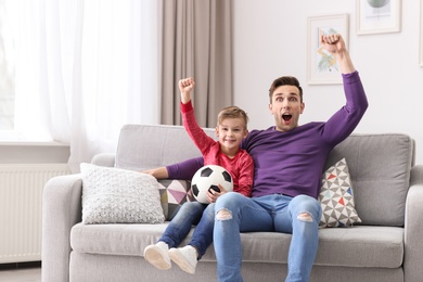Photo of Dad and his son watching football at home
