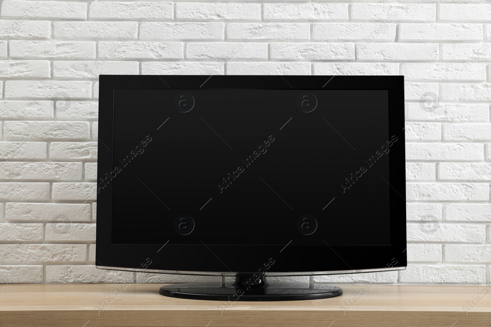 Photo of Modern TV set near white brick wall indoors