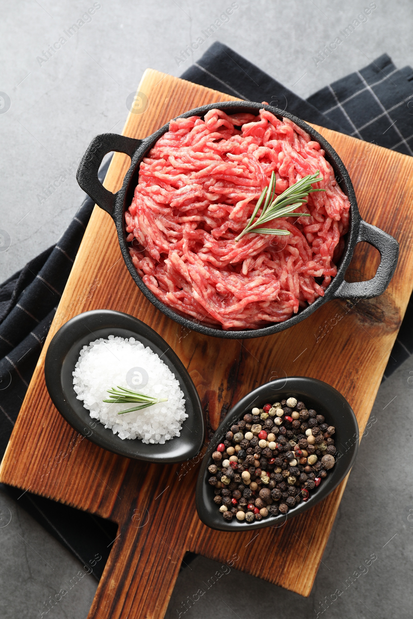 Photo of Raw ground meat in bowl and spices on grey table, top view