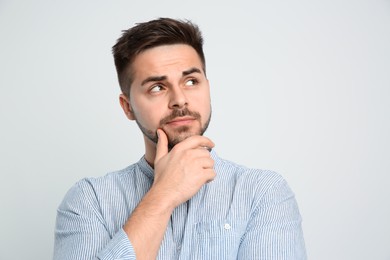 Photo of Pensive man on light background. Thinking about answer for question
