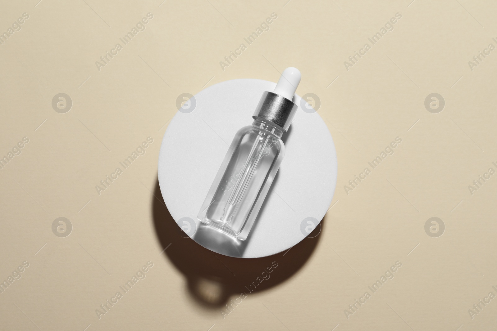 Photo of Bottle of cosmetic oil on beige background, top view