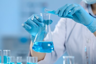 Scientist working with beaker and test tube in laboratory, closeup