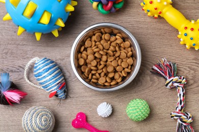 Photo of Flat lay composition with different pet toys and feeding bowl on wooden background
