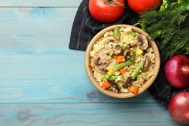 Delicious bulgur with vegetables, mushrooms and other products on light blue wooden table, top view. Space for text