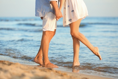 Photo of Happy young couple holding hands at beach on sunny day, closeup