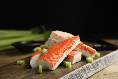 Photo of Fresh crab sticks with celery served on wooden table, closeup