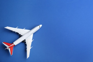 Toy airplane on blue background, top view. Space for text