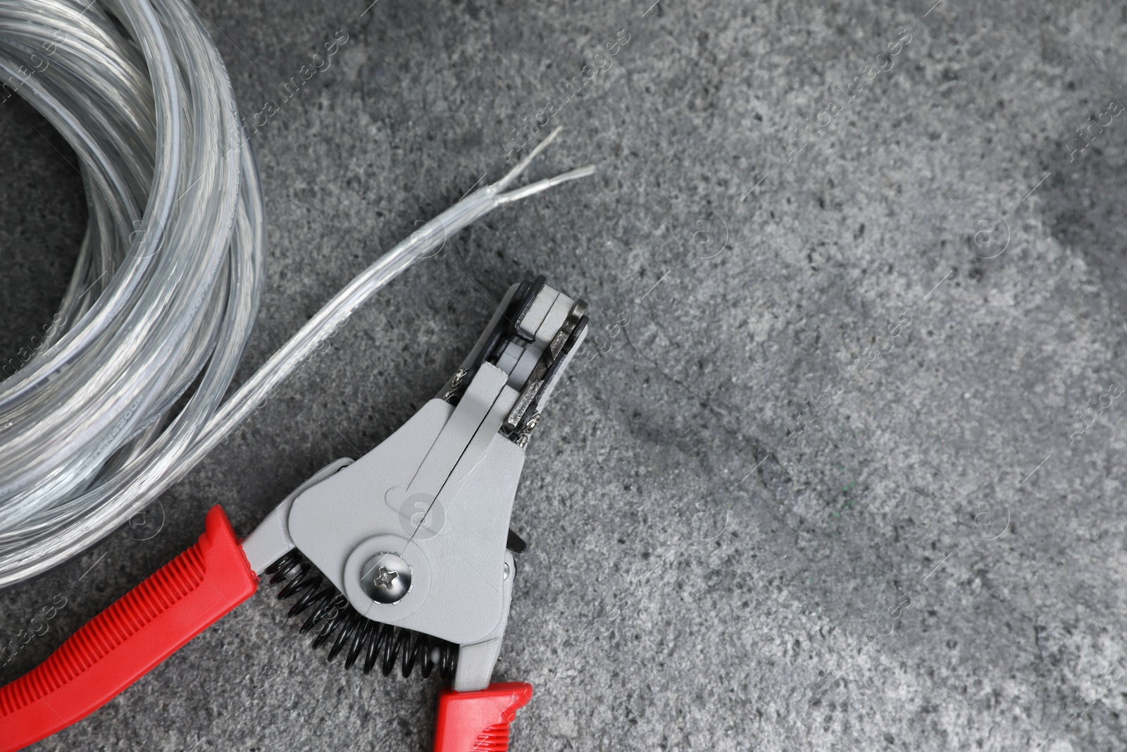 Photo of Cutters and cable with stripped wire on light gray textured table, flat lay. Space for text