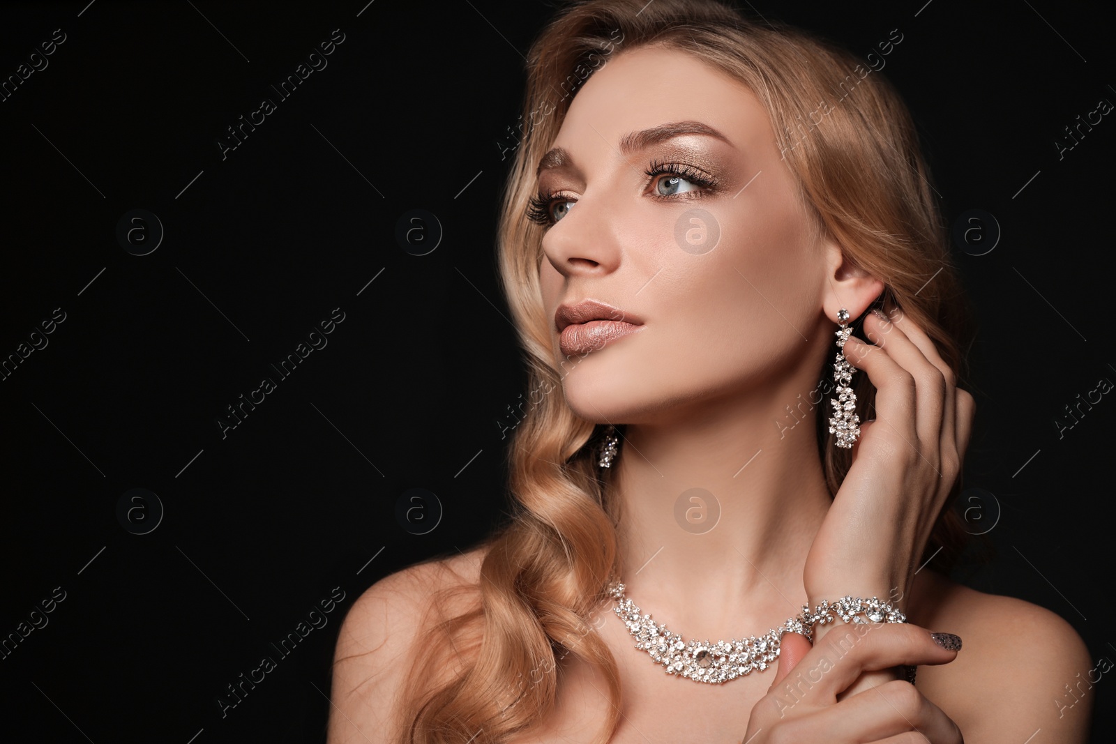 Photo of Beautiful young woman with elegant jewelry on dark background. Space for text