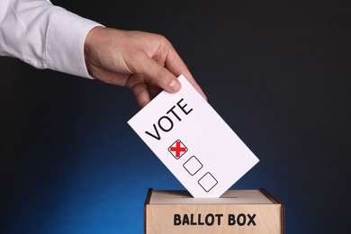 Man putting paper with word Vote and tick into ballot box on dark blue background
