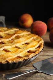 Photo of Delicious fresh peach pie and spatula on wooden table, closeup