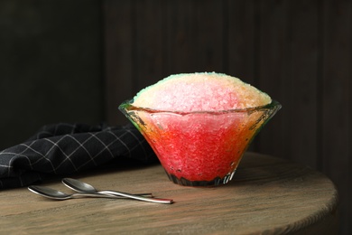 Photo of Rainbow shaving ice in glass dessert bowl on wooden table indoors