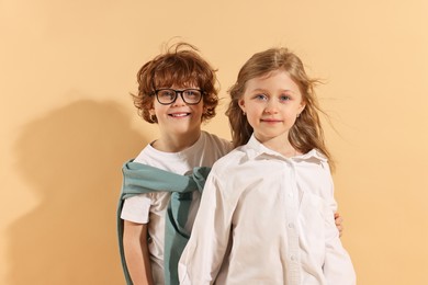 Photo of Fashion concept. Stylish children on pale orange background