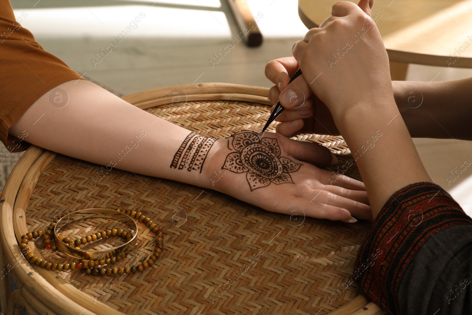 Photo of Master making henna tattoo on hand, closeup. Traditional mehndi