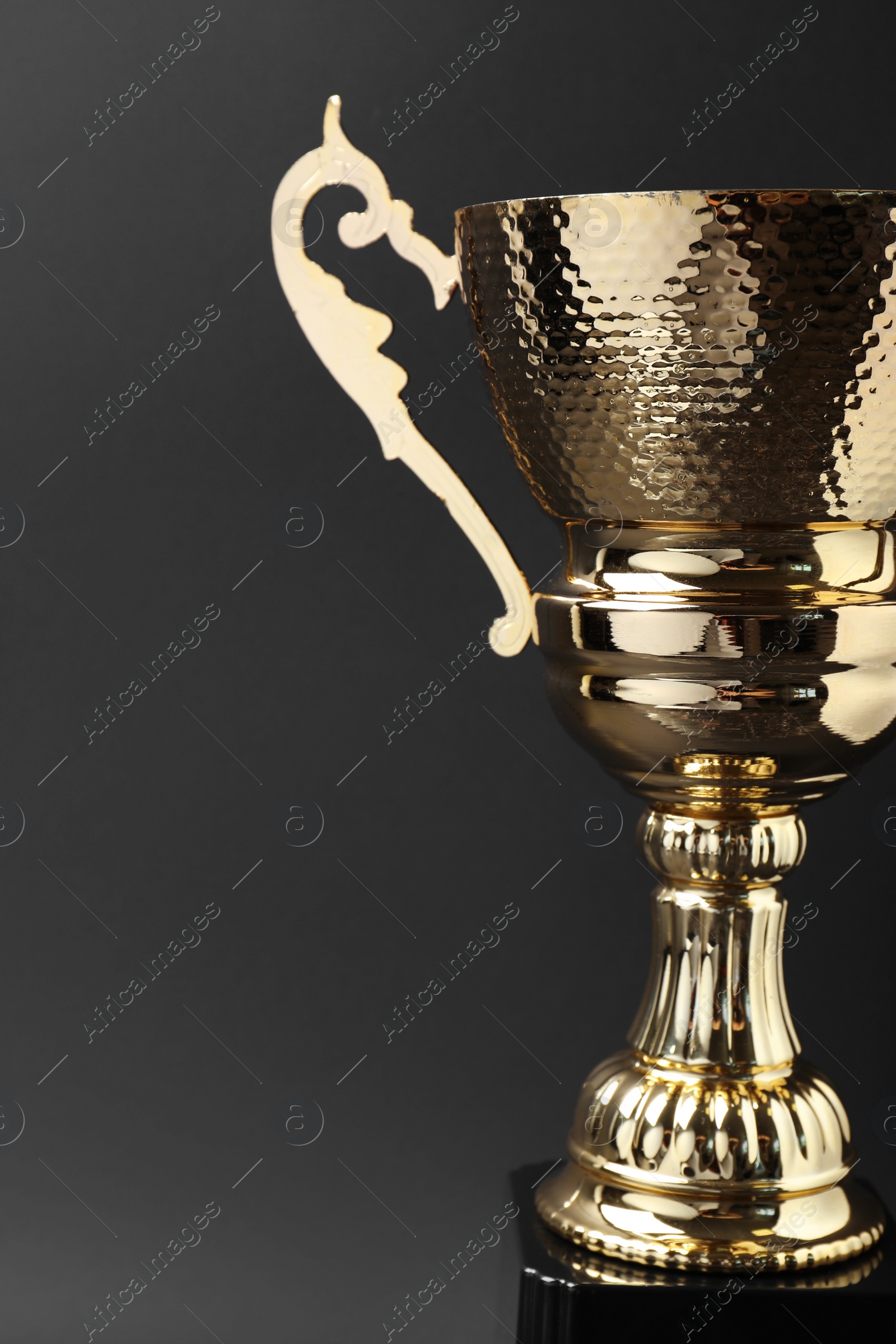 Photo of Shiny golden trophy cup on grey background