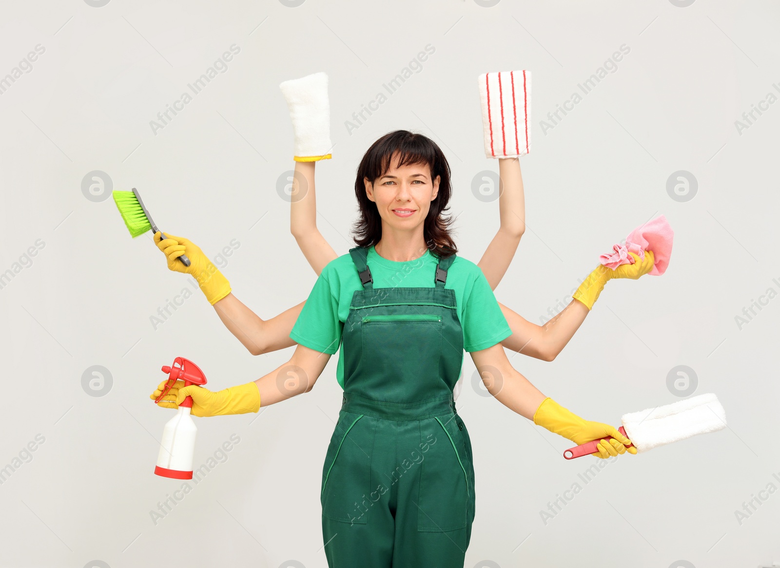 Photo of Woman with many hands holding cleaning supplies on light background