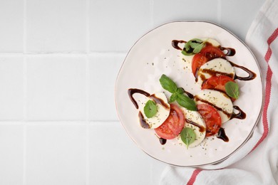 Delicious Caprese salad with balsamic vinegar on white tiled table, top view. Space for text