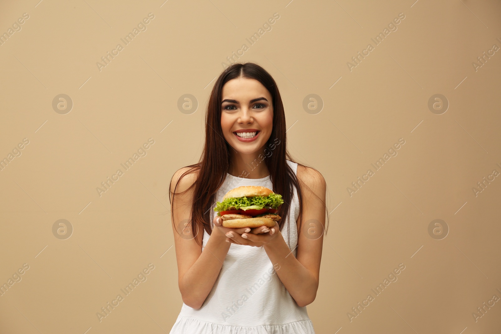 Photo of Young woman with tasty burger on color background