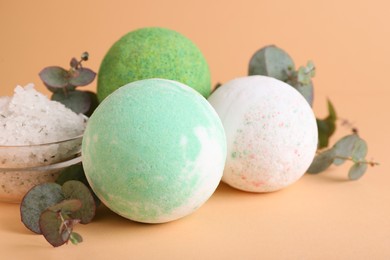 Photo of Colorful bath bombs, salt and eucalyptus branches on beige background, closeup