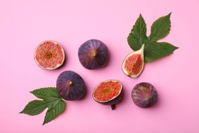 Fresh ripe figs with green leaves on pink background, flat lay