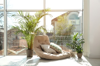 Photo of Cozy place with armchair pillow and potted plants at home