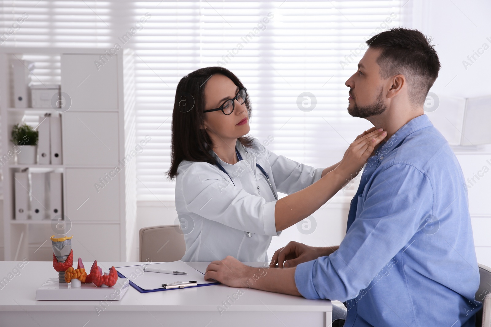 Photo of Doctor examining thyroid gland of patient in hospital