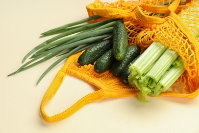 String bag with different vegetables on beige background, closeup