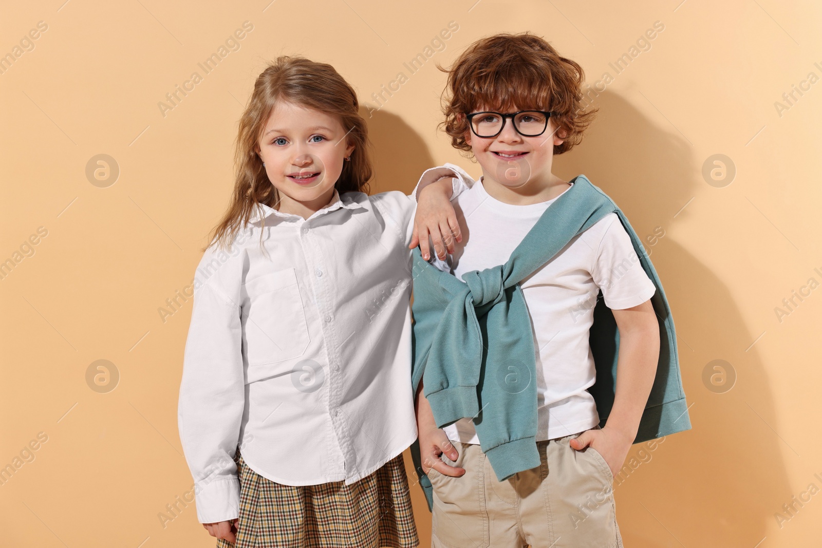 Photo of Fashion concept. Stylish children on pale orange background