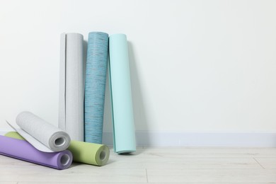 Photo of Different wallpaper rolls near white wall indoors, space for text