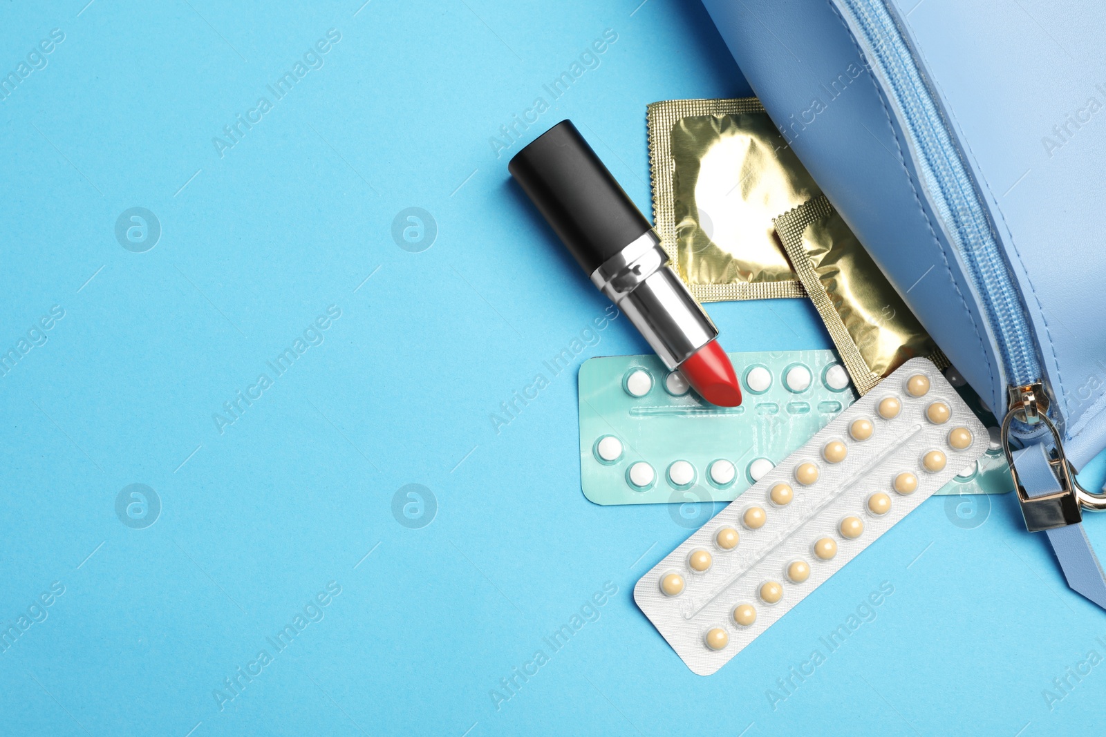 Photo of Flat lay composition with birth control pills and condoms on light blue background, space for text. Safe sex concept