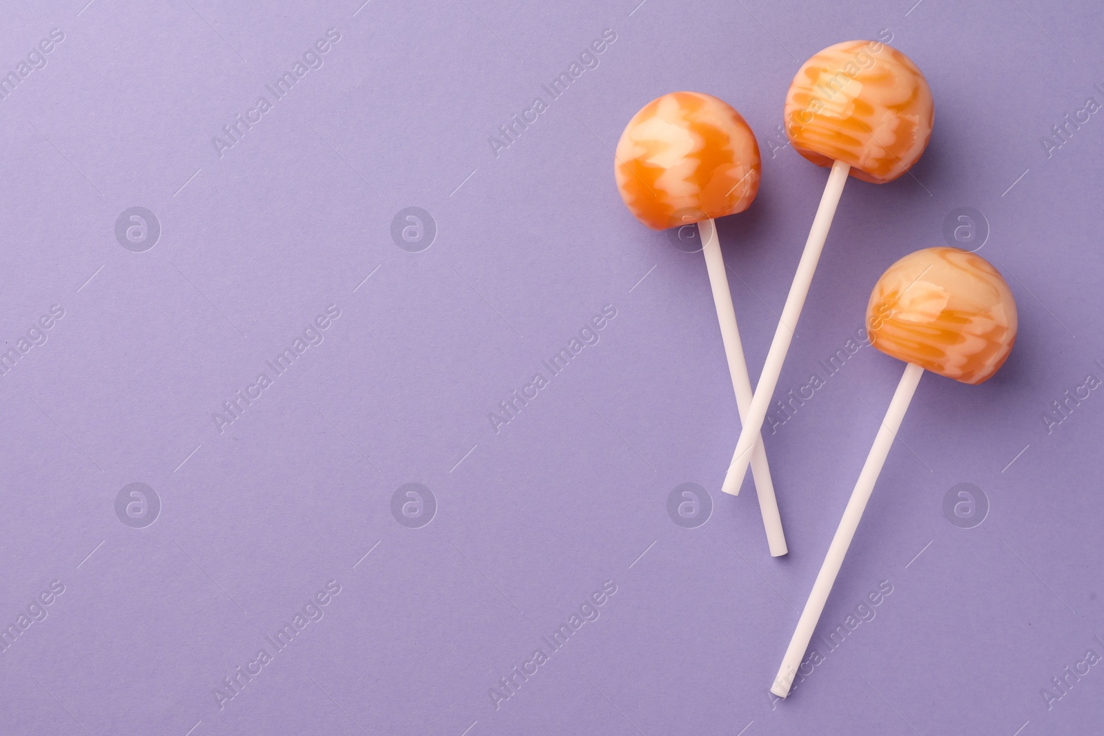 Photo of Tasty lollipops on violet background, flat lay. Space for text