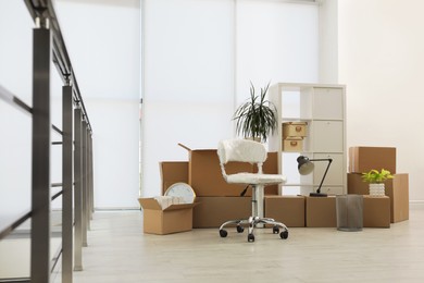 Photo of Cardboard boxes with packed stuff in new office. Moving day