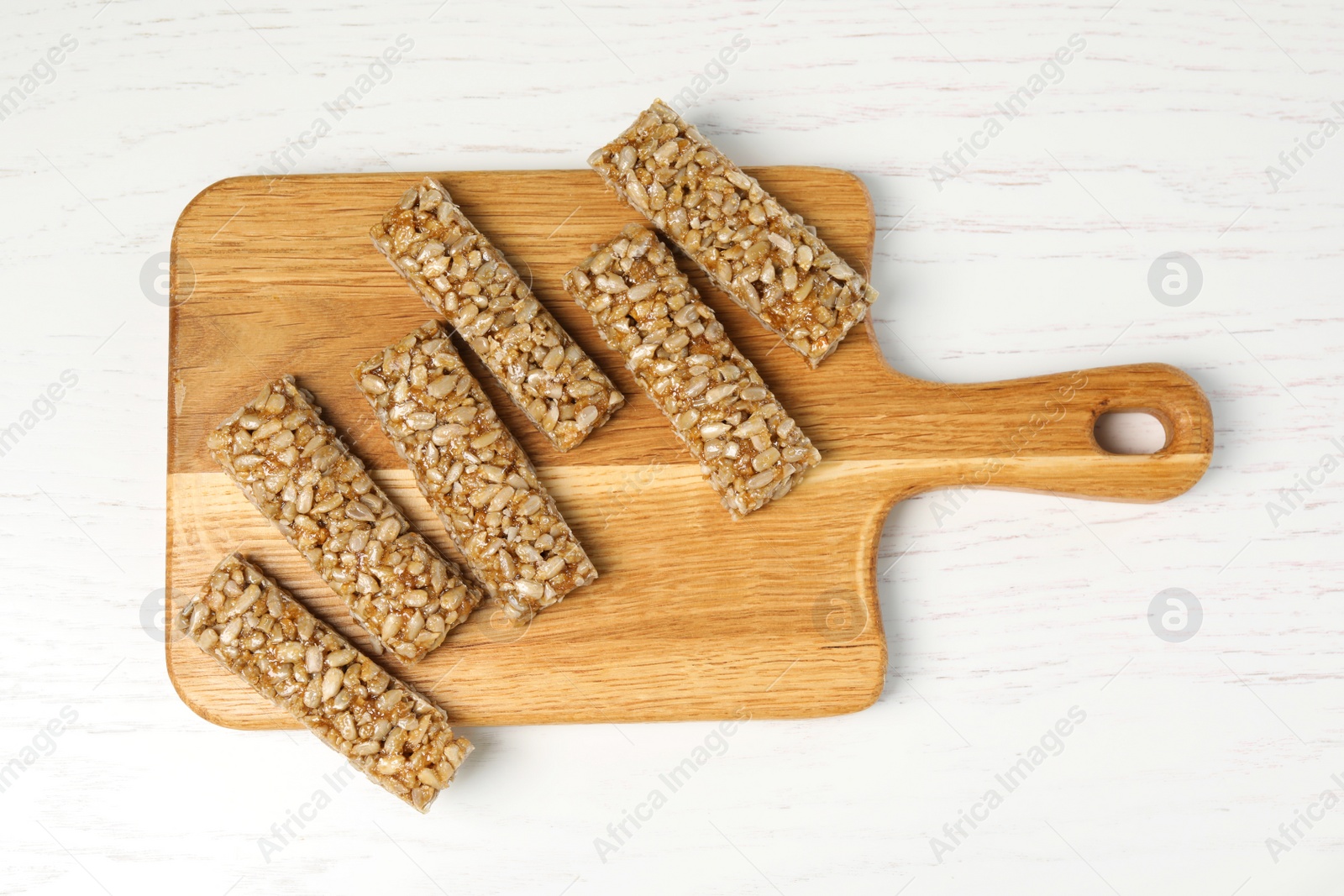 Photo of Delicious sweet kozinaki bars on white wooden table, top view