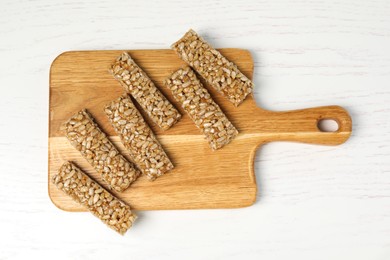 Photo of Delicious sweet kozinaki bars on white wooden table, top view