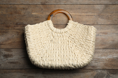 Stylish woman's bag on wooden background, top view