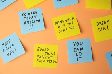 Photo of Paper notes with life-affirming phrases on pale orange background