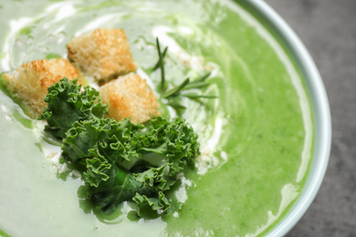 Tasty kale soup with croutons on grey table, closeup