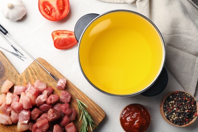 Photo of Flat lay composition with fondue pot and raw meat on light table