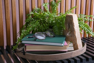 Stylish tray with books, glasses and houseplant on wooden shelf