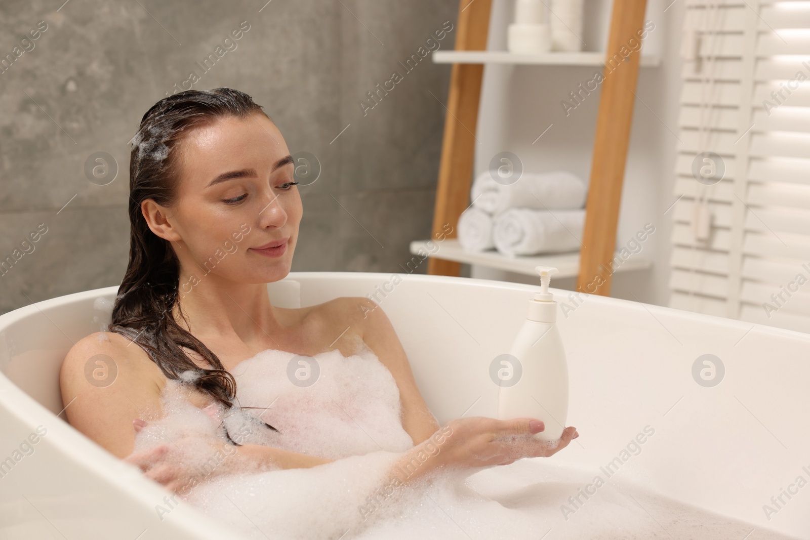 Photo of Woman taking bath with shower gel in bathroom