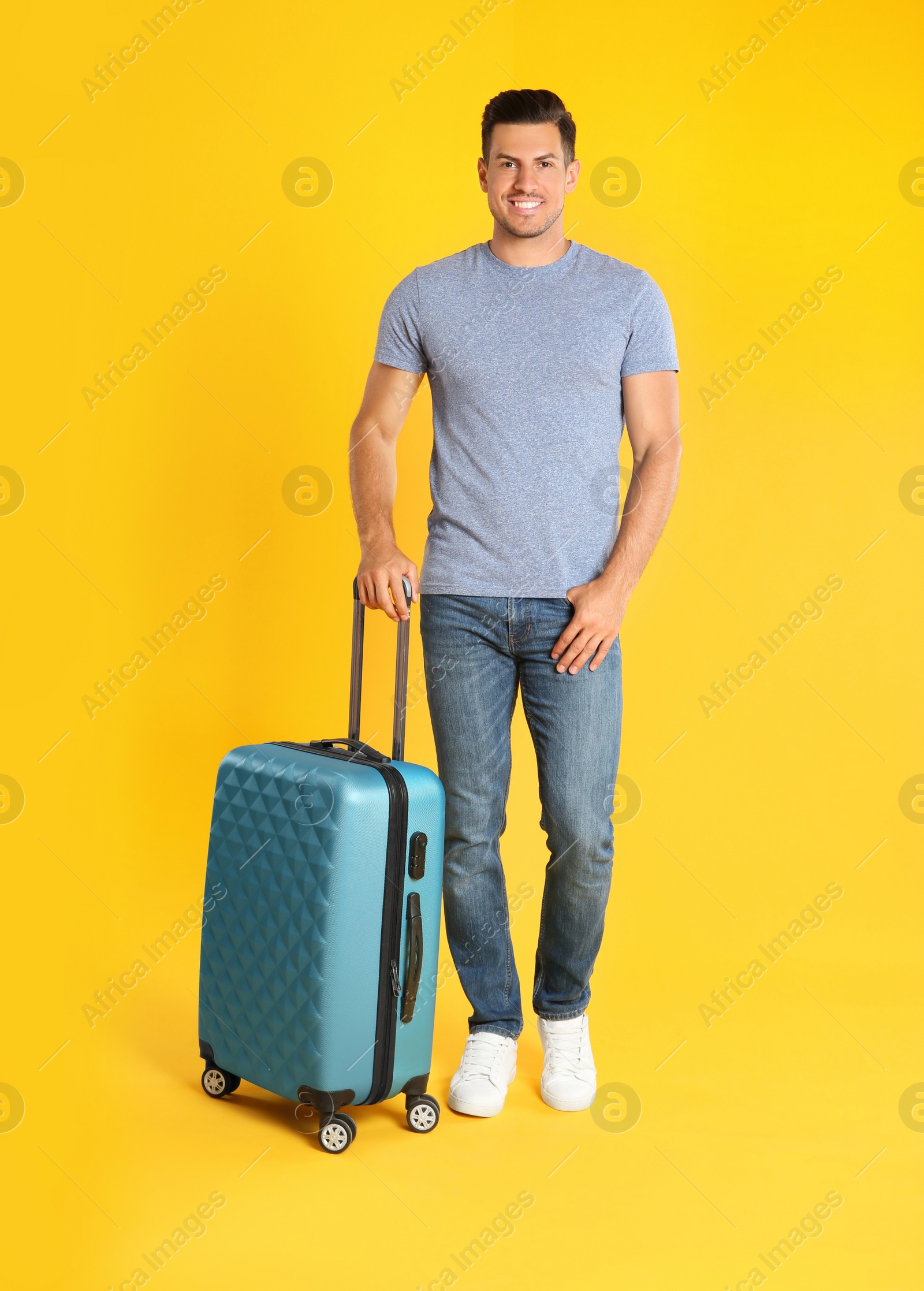 Photo of Handsome man with suitcase for summer trip on yellow background. Vacation travel