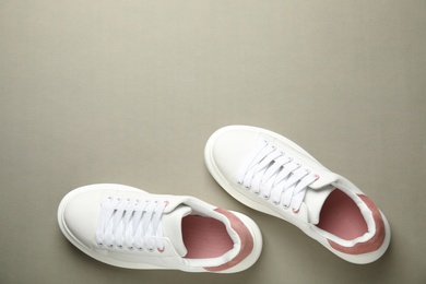 Photo of Stylish white sneakers on grey background, top view. Space for text