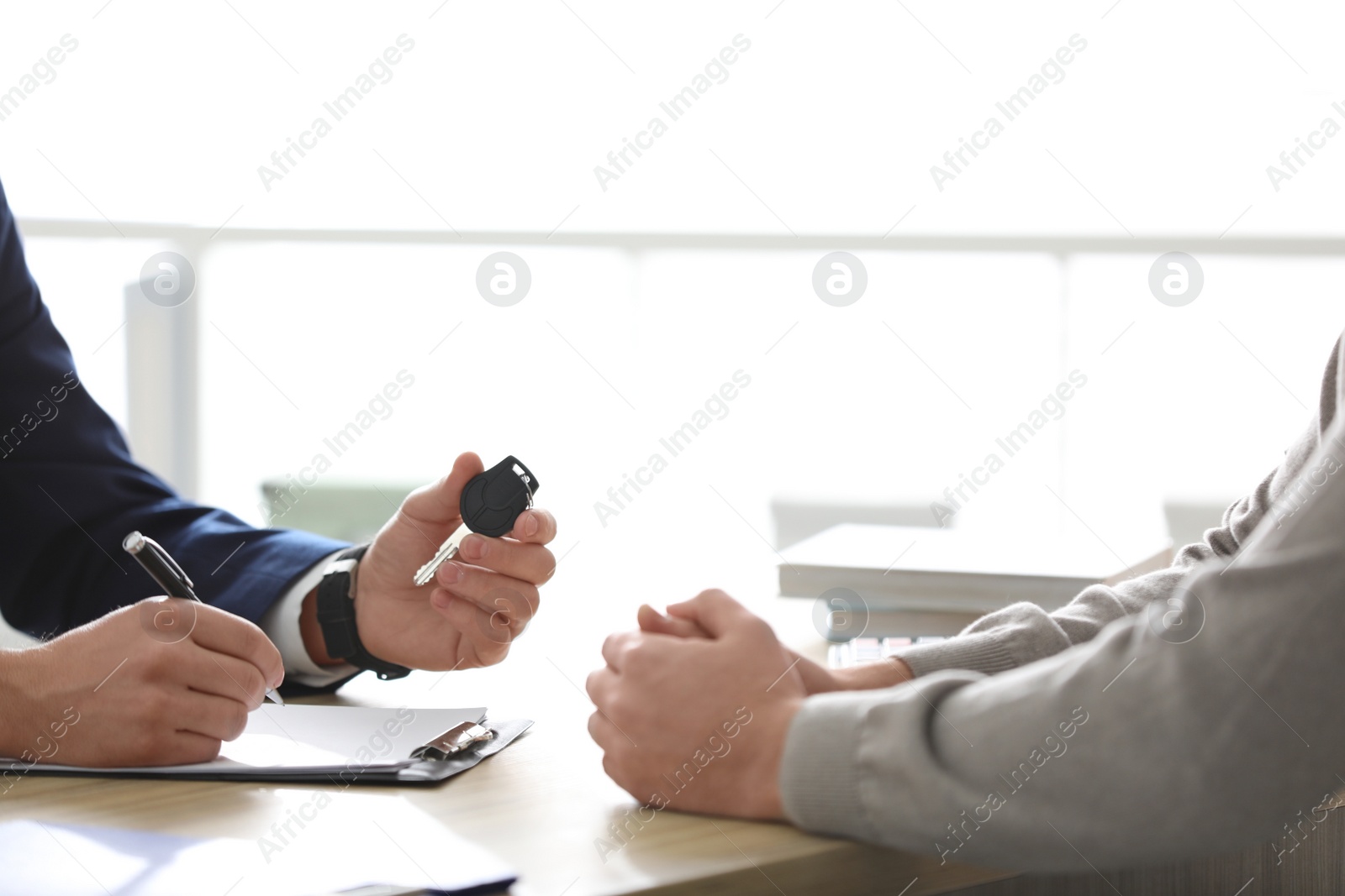 Photo of Salesman giving key to customer in office, closeup. Buying new car