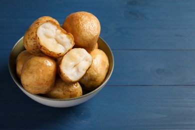 Bowl of tasty whole baked potatoes on blue wooden table, closeup. Space for text