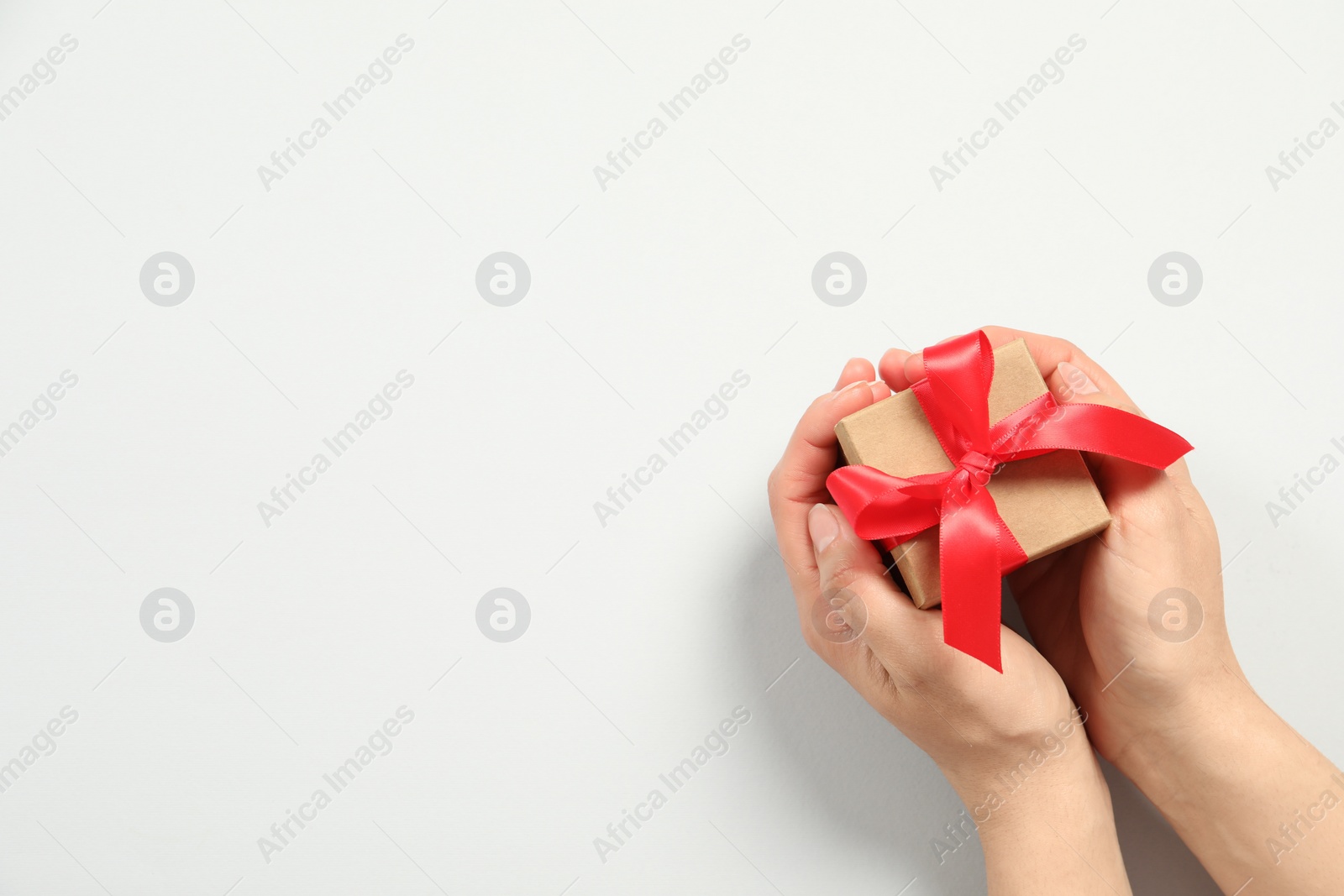 Photo of Woman holding gift box on white background, top view. Space for text