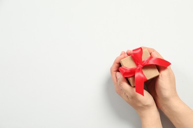 Photo of Woman holding gift box on white background, top view. Space for text