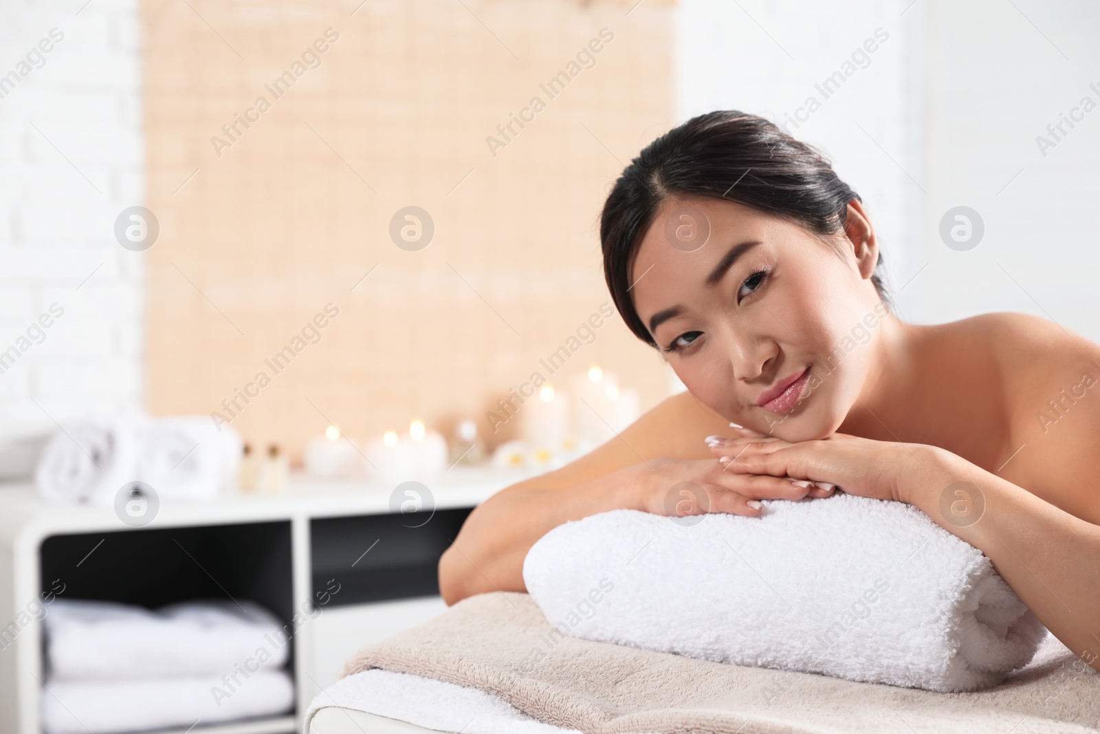 Photo of Beautiful Asian woman lying on massage table in spa salon. Space for text