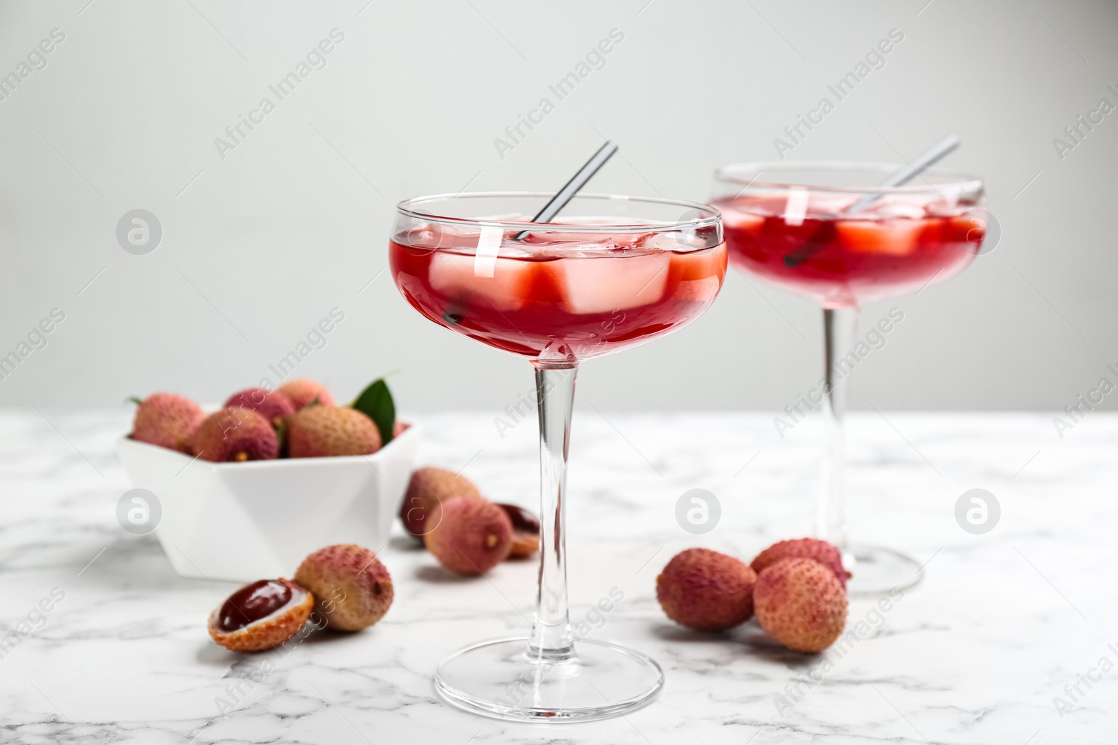 Photo of Delicious lychee cocktails and fresh fruits on white marble table